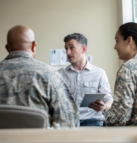 Adult male counselor speaking to a multi-cultural group of soldiers, facilitating a discussion on teamwork and leadership.