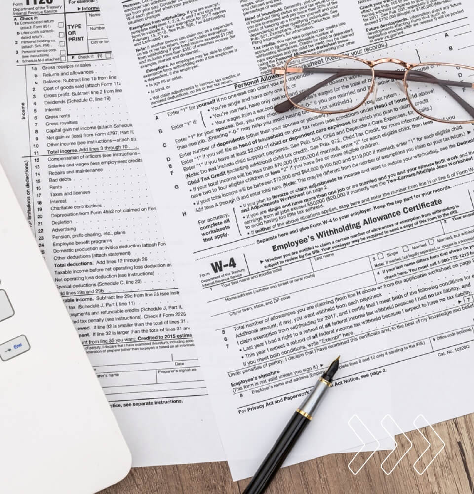 Macro W-4 form with a pen, calculator, and laptop on a desk at American Automator.